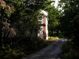Darkly lit road, trees, and building exterior at La Ribaute, Barjac, France.