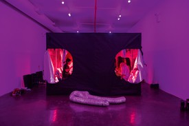 young people inside a tent structure within a purple-lit room