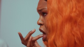 Close up of a person's profile, they have one finger in their mouth